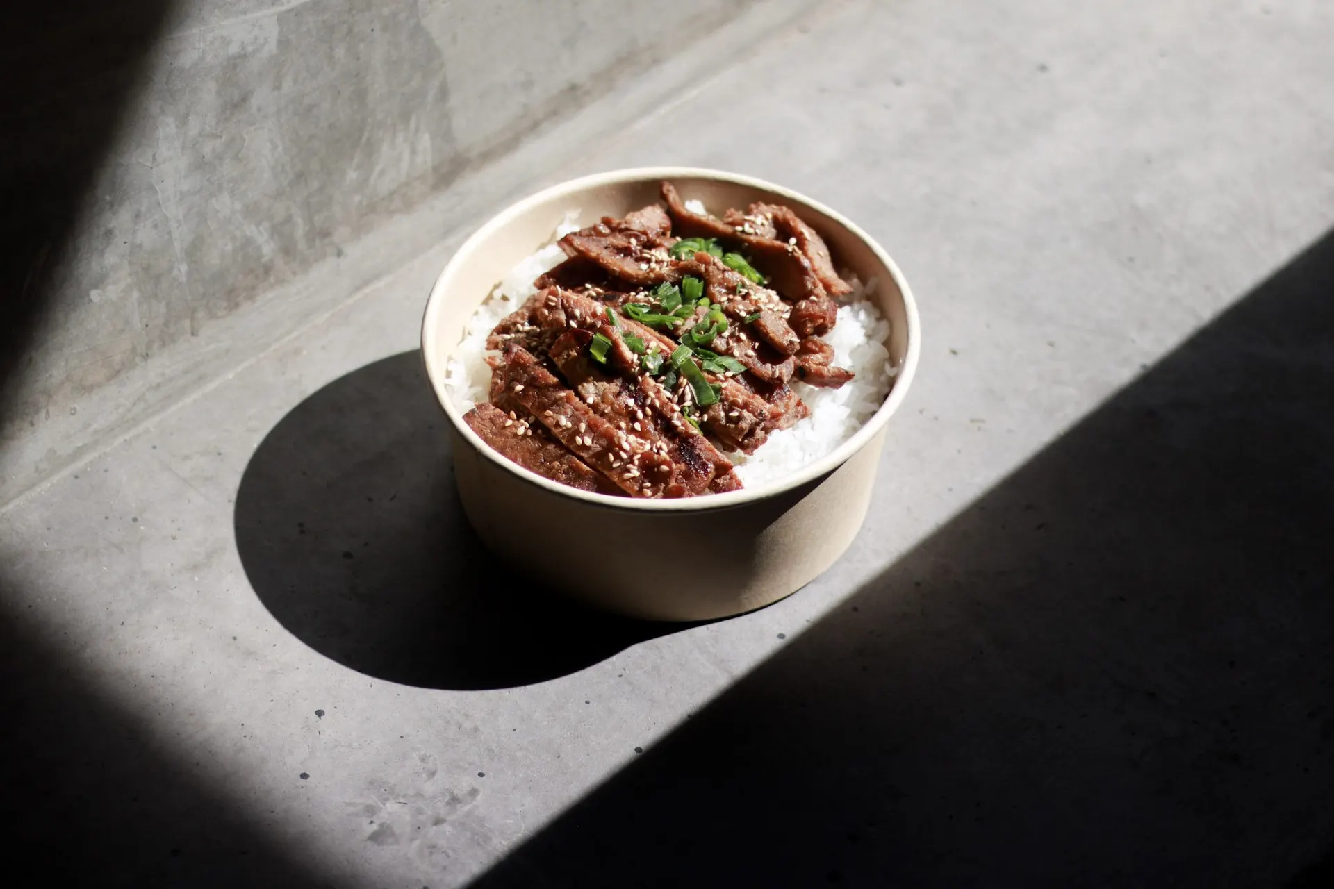 Bowl de carne al grill sobre concreto con sol directo